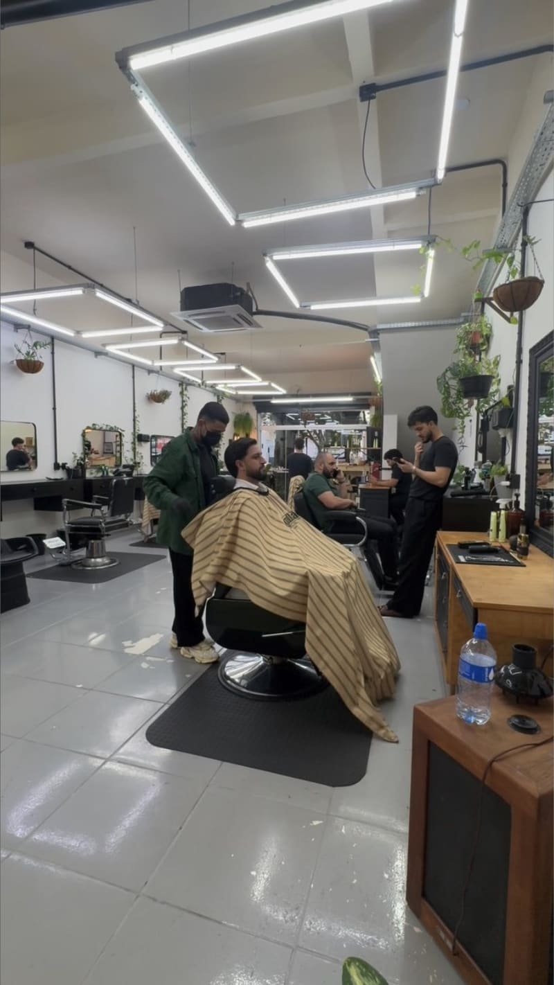 Interior da Barbearia Magalhães, barbearia em Maringá, com barbeiros atendendo clientes